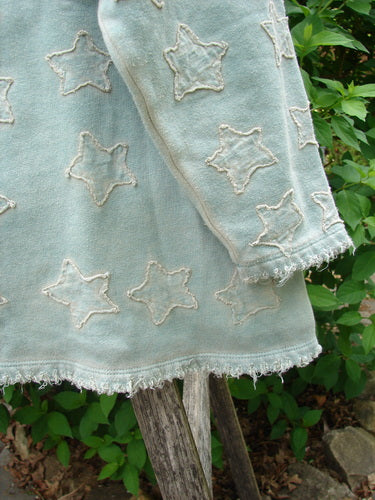 Magnolia Pearl Fleece Applique Little Star Hermosa Sweatshirt Garden Sage OSFA drapes over a post, showcasing its three-quarter wide sleeves, frayed edges, and star appliques, embodying Bluefishfinder.com's vintage, expressive style.