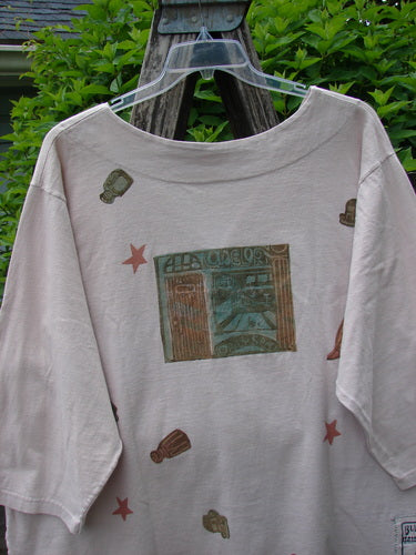 1993 Resort PJ Top Diner Treat Tea Dye Size 2, featuring scattered graphics and a central storefront print, hangs on a clear hanger. Notable for its V-neckline, long sleeves, and signature Blue Fish patch.