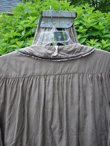 Magnolia Pearl Silk Cotton Poet's Billow Blouse elegantly displayed on a clear hanger against a rustic wooden rack, showcasing its flowing design, rounded lace collar, and billowy sleeves with snap cuffs.