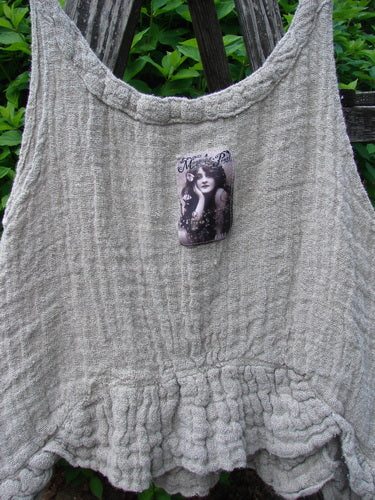 Magnolia Pearl Fisherman's Weave Ribbon Neck Top Flaxen OSFA displayed on a wooden bench, showcasing its scalloped hem and vintage-style portrait patch, embodies the creative, expressive spirit of Bluefishfinder.com.