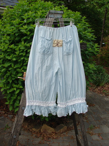 Magnolia Pearl Silk Voile Window Lace Ruffle Pocket Bloomer Sky OSFA, loose-fitting knee-length pantaloons with lace ruffle hems, hanging outdoors on a wooden ladder, showcasing dual window lacings and patch pockets.