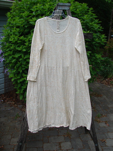 Magnolia Pearl Cotton Dylan Dress Softest Floral Naranja OSFA, off-white with subtle floral print, hangs on a wooden ladder, showcasing long sleeves, A-line flair, and distressed seams against a green outdoor backdrop.