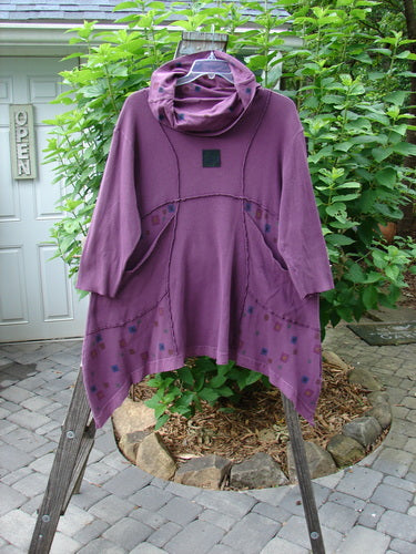 Barclay Patched Thermal Cowl Turtleneck Tunic in Dusty Red Plum on a wooden stand, showcasing its floppy cowl neck, curved stitchery, and oversized pockets.