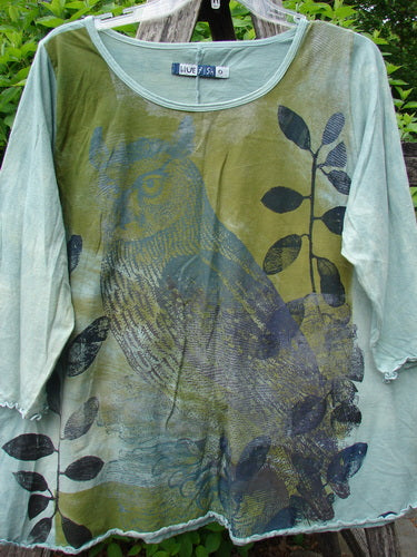 Barclay Three Quarter Sleeved Cafe Tee Owl Forest Mottled Mint Size 0, featuring a stylized owl and leafy-branch motifs on the front, hangs outdoors, showcasing its A-line shape and curly edgings.