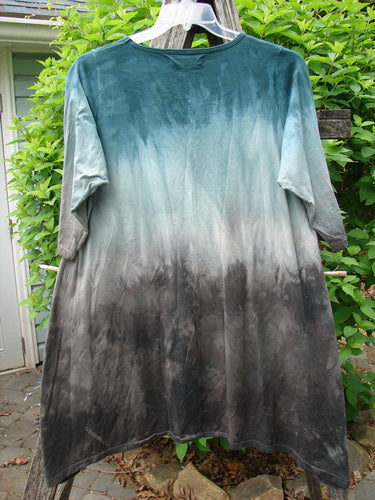 Barclay Wander Tunic Tee Magic Mottled Vintage Teal Size 0, featuring a dip-dyed ombré effect from teal to dark gray, displayed on a hanger outdoors against green shrubs and stone paving.