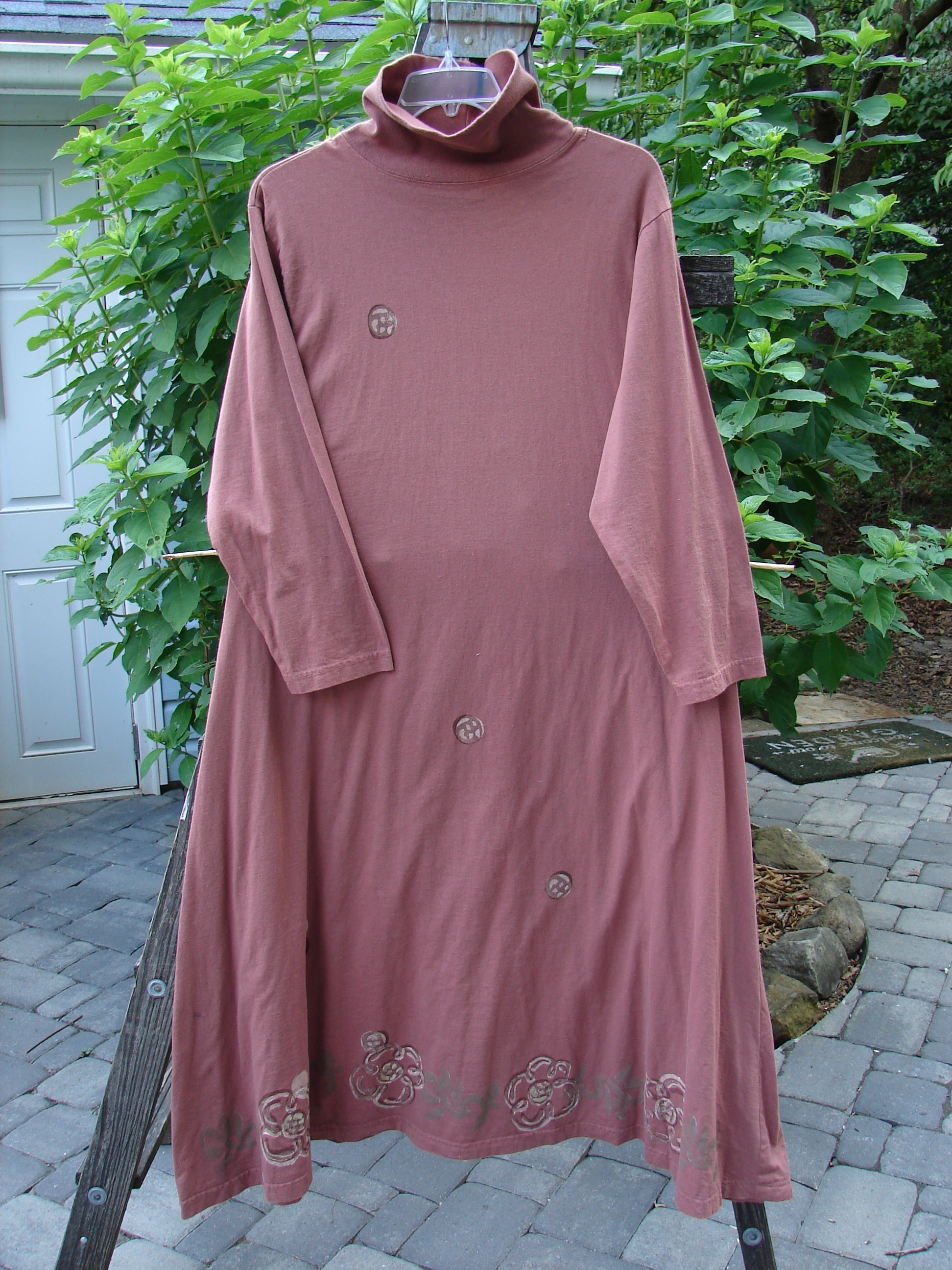 1995 Omega Dress Celestial Garden Altered Clove Size 1, hung on a wood pole, showcasing a heavy ribbed turtleneck, drop shoulders, and a serious A-line flare with a drawcord backline.