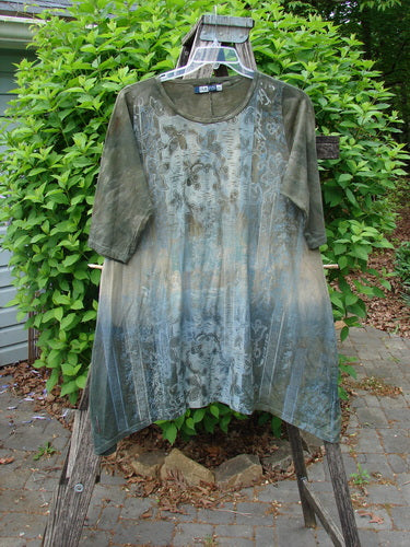 Barclay Wander Tunic Tee Botanicals in Mottled Vintage Hunter features a loose fit, asymmetrical hem, and floral print. Crafted from organic cotton, it hangs outdoors, showcasing its unique design.
