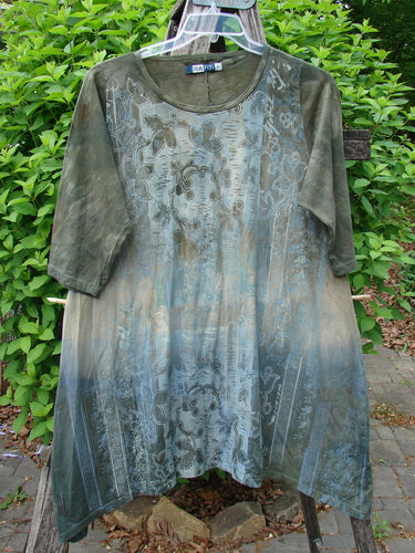 Barclay Wander Tunic Tee Botanicals Mottled Vintage Botanicals Hunter Size 0, featuring a loose fit, three-quarter sleeves, and a floral scrollwork pattern, hanging outdoors against leafy shrubs.