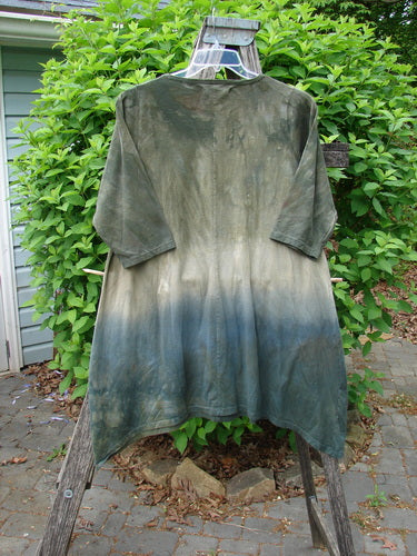 Barclay Wander Tunic Tee Botanicals Mottled Vintage Hunter Size 0, featuring a gradient dip-dye from dark olive to bluish hue, hangs on a wooden frame, showcasing its unique design and A-line flair.