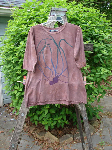 A Barclay Cotton Lycra Three Quarter Sleeved A Line Tee in Mottled Clay hangs on a ladder, featuring a blue/teal abstract design and purple circles, embodying Bluefishfinder's artistic vintage style.
