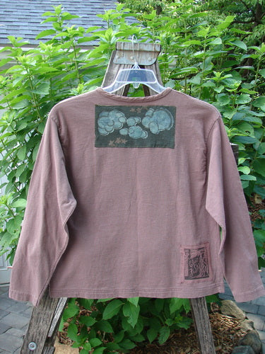 1994 PMU Patched Long Sleeved Tee Rosewood Size 1 displayed on a hanger, showcasing its boxy cut, rolled neckline, cozy long sleeves, and distinctive playground and cloud-themed patches.
