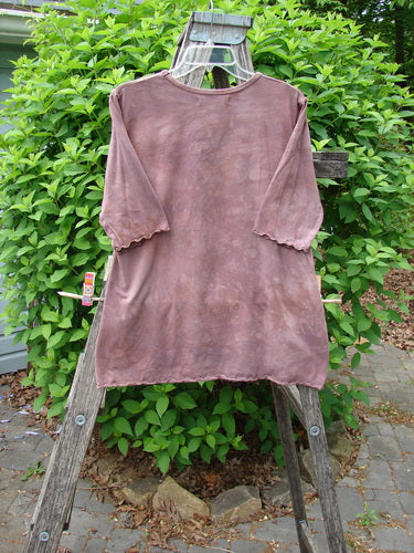 Barclay Cotton Lycra Three Quarter Sleeved A Line Tee Roots Mottled Clay, draped on a wooden ladder. Features include scalloped cuffs, a rounded neckline, and an A-line shape, highlighting vintage style.
