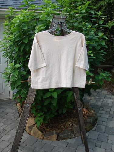 Barclay PMU Patched Short Sleeved Crop Tee Fish Creme Size 0 displayed on a wooden swing, showcasing its boxy shape, hand-stitched crop length, and distinctive fish patch.