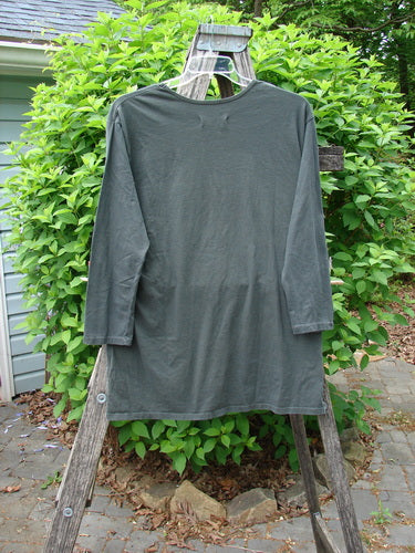 Barclay Long Sleeved Studio Tee Moon Gull Garden Ash Black Size 0, displayed draped over a wooden step ladder, showcases its straight, boxy shape and thinner flattened neckline against a garden backdrop.