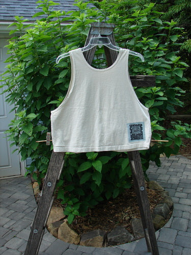 1999 PMU Patched Tank Top Wave Natural Size 1 displayed on a wooden rack, showcasing its scooped neckline and colorful wave-themed patch.