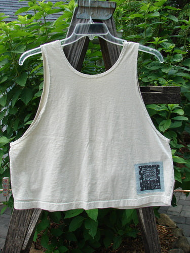 1999 PMU Patched Tank Top Wave Natural Size 1 displayed on a plastic mannequin on a wooden swing, showcasing its wide boxy shape, scooped neckline, and signature Blue Fish patch.