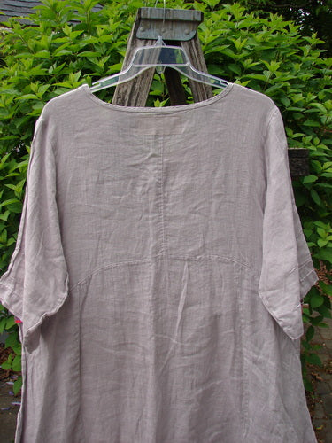 Barclay Linen Wave Pocket Dress Fern Mallow Quartz Size 0 hangs on a ladder, showcasing its loose-fitting design, rounded neckline, seamless bodice, pinched sleeves, and drop pockets.