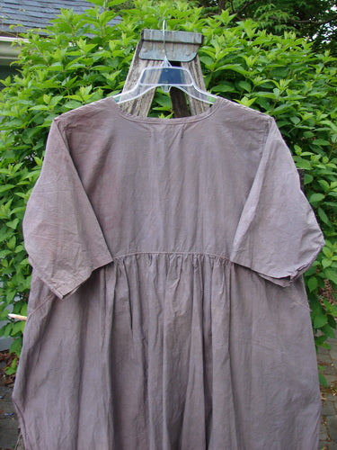 Barclay Percale Key Pocket Hi Low Dress Floral Burst Mocha Size 0, featuring a key neckline, elbow-length sleeves, and gathered waist. Displayed on a hanger with green foliage background, highlighting its summery, hand-dyed design.