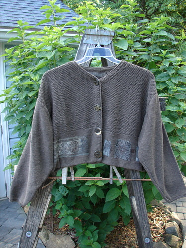 1994 Crop Cardigan Sweater Topiary Humus OSFA displayed on a swing, showcasing its unique texture, stoneware buttons, contrasting knits, and cozy longer sleeves with a V-shaped neckline.