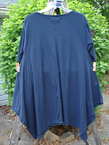 Barclay Origami Tunic Top Night Garden Blue Ink Size 0 showcased on a hanger, highlighting its loose fit, open sides, and varying hemline against greenery. Features raw edges and an oval neckline.