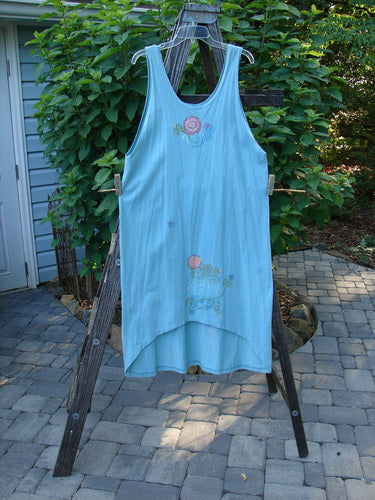 Barclay Scoop Front River Journey Dress Fancy Floral Blue Tourmaline Altered Size 1 displayed on a wooden rack, showcasing its deep scoop neckline, straight shape, and floral design.
