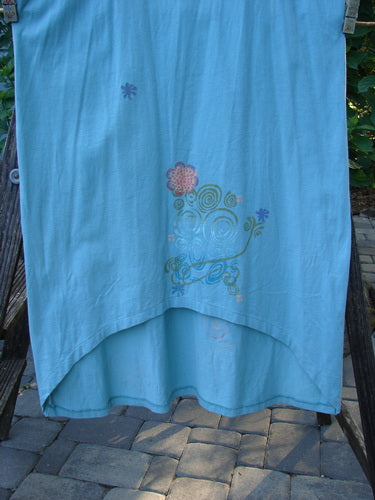 Barclay Scoop Front River Journey Dress in Blue Tourmaline with a deep scoop neckline, straight elongating shape, and upward scoop front hem, hanging on a clothesline.