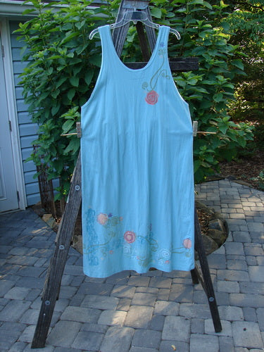 Barclay Scoop Front River Journey Dress Fancy Floral Blue Tourmaline Altered Size 1 displayed on a wooden ladder. Features deep scoop neckline, deeper arm openings, and an upward scoop front hemline.