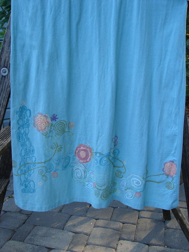 Barclay Scoop Front River Journey Dress in Blue Tourmaline with floral theme, medium-weight organic cotton, deep scoop neckline, altered Size 1, displayed on a wooden stand.