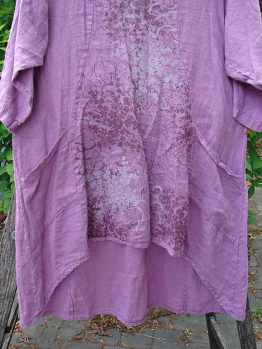 Barclay Linen Posey Dress Tiny Floral Orchid Size 0 draped on a wooden hanger, showcasing its flowy figure-eight shape, long sleeves, and two front pockets, with a delicate floral motif.