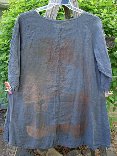 Barclay Linen Lucida Top in Metallic Fern Blue Storm, Size 0, displayed outdoors with rust-brown staining on the back, features a flowy A-line shape and almost three-quarter sleeves.