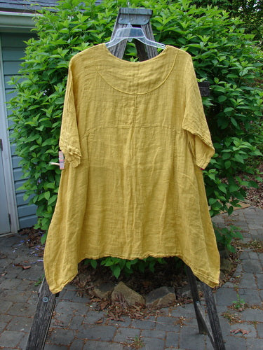 Barclay Gauze Linen Cross Over Dress Unpainted Sunshine Spice Size 1, displayed on a ladder, features a soft V neckline, drop shoulders, double pockets, and asymmetrical hem, embodying Bluefishfinder.com's artistic vintage style.