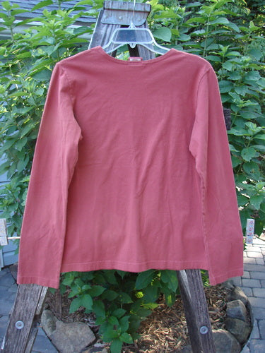 Barclay Cotton Lycra Long Sleeved Layering Top Unpainted Brick Size 1 displayed on a wooden fence, showcasing its rounded neckline and longer sleeves.