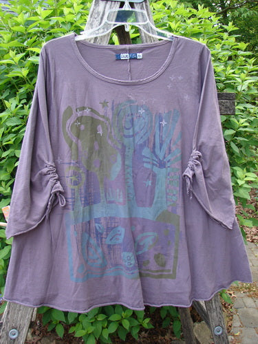 Barclay Draw Gather Sleeve Cafe Top Power Plum Size 0 hangs on a clear hanger, showcasing its scoop-neck, tunic style with drawstring ruching and abstract folk-art design in darker hues.