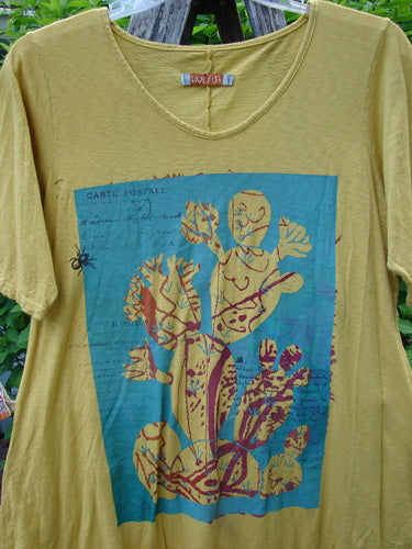 Barclay Slub Short Sleeved Travel Tee Cactus Garden Citron Size 1 features a stylized cactus print with CARTE POSTALE script, short sleeves, and a unique hem, displayed outdoors on a hanger.