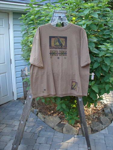 1998 Men's Short Sleeved Tee Sailboat Rock Brown Size 2 XL displayed on a wooden rack, showcasing a classic sailboat theme with a softly thicker ribbed neckline and signature Blue Fish patch.