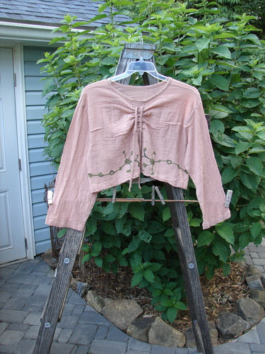 Barclay Limited Edition Gauze Waterfall Crop Top Vine Blush Size 1 displayed on a wooden stand outdoors, showcasing its rounded neckline, drawcord, widening A-line hem, crop length, wide longer sleeves, and drop shoulder.