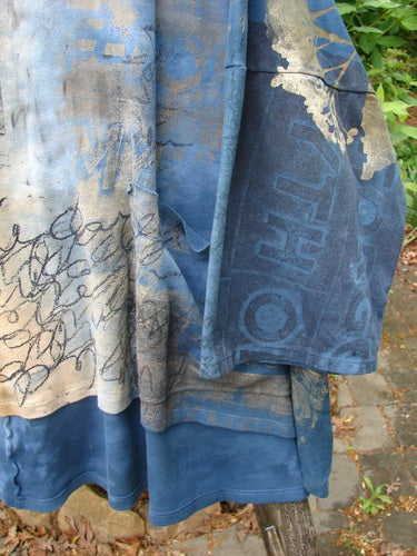 Barclay Writer's Pocket Pullover Future Night to Day OSFA, featuring scribbled designs and a rounded neckline, lies draped over a wooden rail, showcasing its seamless, dynamic art in a relaxed outdoor setting.