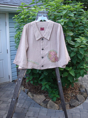 Barclay Linen Metal Button Big Collar Jacket Carnation Wheat Size 1 displayed on a wooden rack, showcasing a sailor-like collar, wide V-shaped neckline, and wider cuffable lower sleeves with carnation-themed paint.