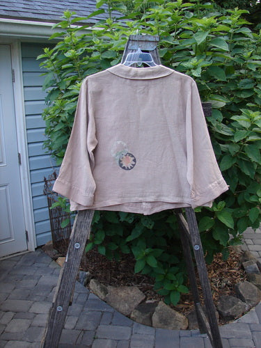 Barclay Linen Metal Button Big Collar Jacket Carnation Wheat Size 1 displayed on a wooden rack, showcasing its wide V-shaped neckline, sailor-like collar, and full metal button front.