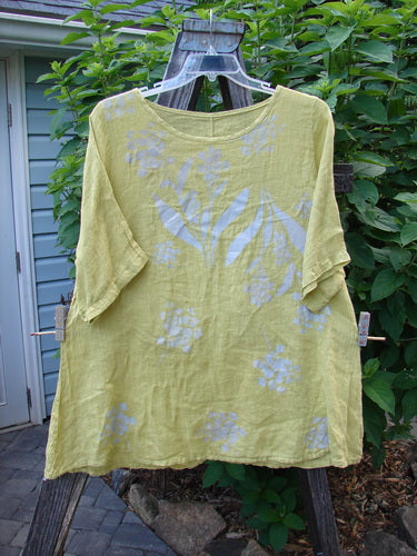 Barclay Light Weight Linen A Line Top Hyacinth Sunshine Size 1 displayed on a wooden hanger, featuring a rounded neckline, slight A-line fall, three-quarter sleeves, and a continuous hyacinth pattern.