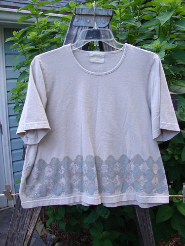 2000 Short Sleeved Crop Tee Floral Fence Dove Size 0, displayed on a clothesline, showcasing sweet floral fence theme, wider neckline, and super wide crop box shape made from mid-weight organic cotton.