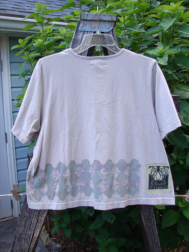 2000 Short Sleeved Crop Tee Floral Fence Dove Size 0 displayed on a wooden hanger, showcasing its wide crop box shape, sweet floral fence paint, and signature Blue Fish patch.