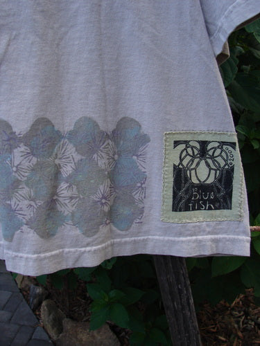 2000 Short Sleeved Crop Tee Floral Fence Dove Size 0—close-up showing floral fence pattern, wide flat neckline, and signature Blue Fish patch, emphasizing the unique design and quality of the mid-weight organic cotton fabric.