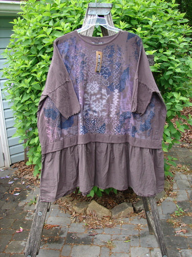 Barclay NWT Batiste Banded Flounce Esperanza Tunic Festive Garden Sparrow OSFA displayed on a wooden ladder, showcasing its patchwork bodice, raglan sleeves, and tiered ruffle hem with attached tag.