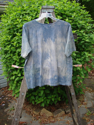 Daisy Hagey Barclay Fiona Straight Tee Tree Mottled Window Pane Size 0 in mottled blue-gray and white, shown hanging on a wooden rack against green foliage.