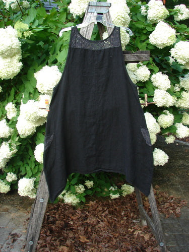 Bluefishfinder.com Barclay NWT Summercloth Lace Two Pocket Pinafore Floral Fern Black Size 0, a black sleeveless pinafore with a lace yoke and two side pockets. The airy fabric hangs from a wooden frame, with white hydrangeas and green foliage filling the background.