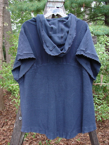 Barclay Celtic Moss Hooded Pocket Cardigan Unpainted Navy Storm Size 0 displayed on a clothes rack, featuring a floppy hood, short sleeves, two exterior pockets, curly edges, and a full button front.
