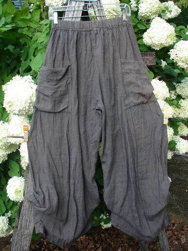 Bluefishfinder.com Barclay Linen Tie Bottom 4 Square Pant Cross Dye Army in unpainted size 0, shown as loose gray linen pants with a gathered elastic waist, oversized square patch pockets, and tie-bottom hems. The crinkled fabric hangs in a soft, draped silhouette.