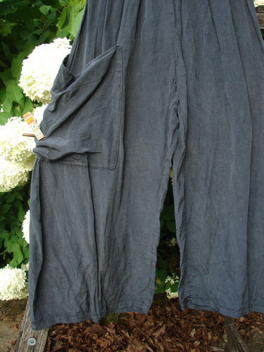 Bluefishfinder.com Barclay Silk Dimensional Pant in unpainted black, size 1, with a loose drape and wide legs in a softly wrinkled silk finish. The pants hang against leafy greenery and white flowers, with a visible side pocket and a muted, textured surface.