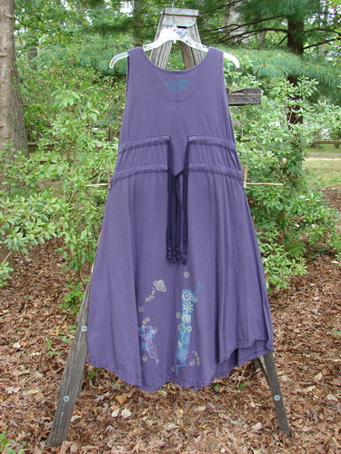 1994 Spin Jumper Mixed Purple Nuit Size 2 on a wooden rack, featuring a long skirt, deep V neckline, and sweeping hemline adorned with nature-inspired designs.